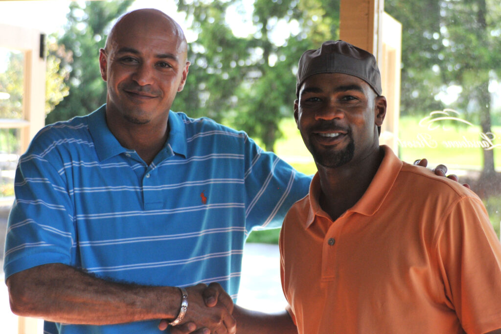 two men wearing casual clothing shaking hands