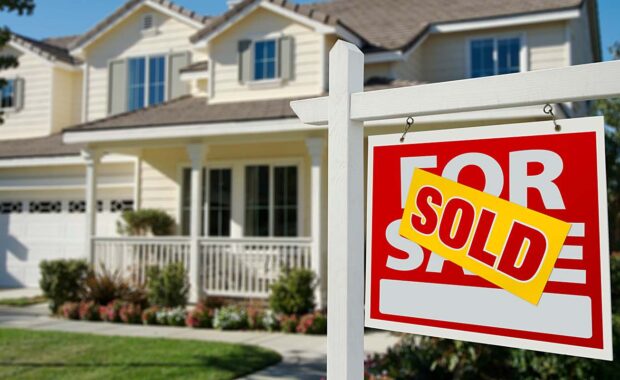 house with sold sign in the front lawn