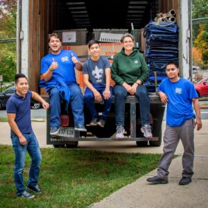 volunteers sitting on back of movingtruck