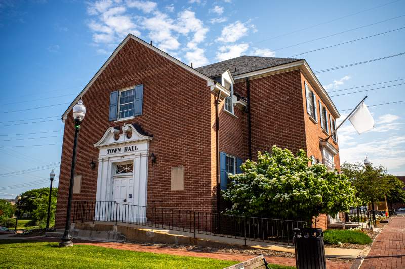 Under a serene blue sky, capture a side view of Herndon, Virginia's City Hall, epitomizing the town's charm and civic pride.