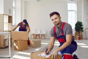 moving service workers pack cardboard boxes and checking list in client's apartment