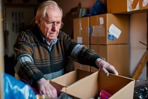 old man packing unwanted things in a wooden box