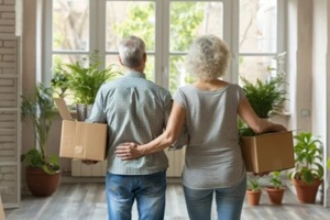 senior couple moving in, unpacking boxes in new home with plants, real estate relocation concept