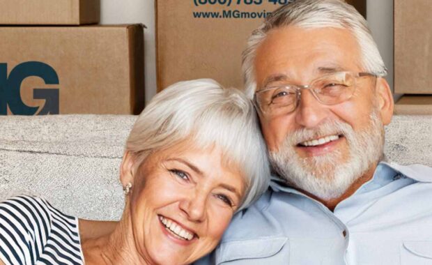 two senior adults sitting on a couch with mg moving boxes in the background