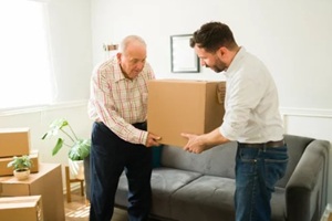 man helping senior man packing boxes