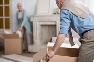 side view of man holding cardboard box and helping wife unpack things