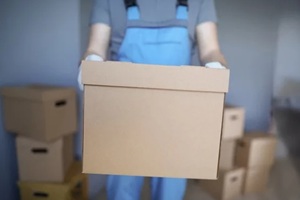 close-up of worker loading cardboard boxes with owners belongings to new apartment