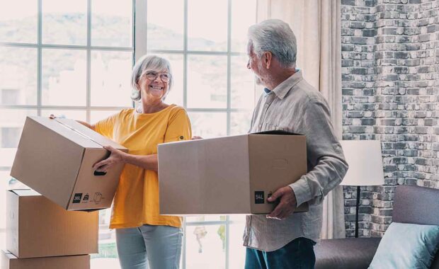 senior couple holding moving boxes