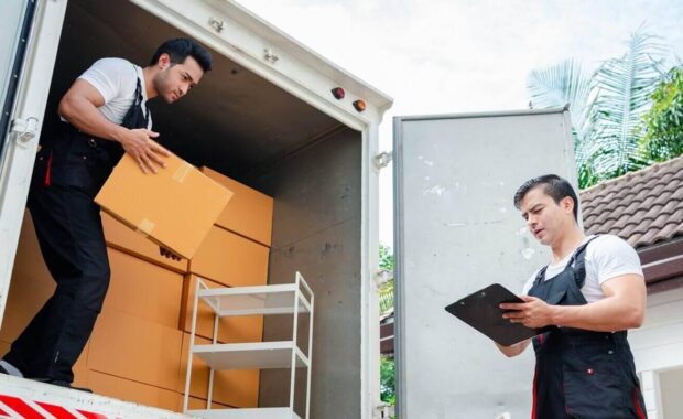 unloading boxes and furniture from a pickup truck to a new house with service cargo two men movers worker in uniform lifting boxes