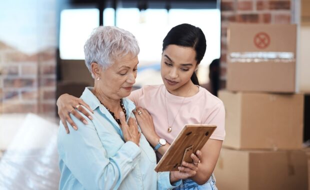 senior woman looking at a photograph with her daughter while packing boxes on moving day