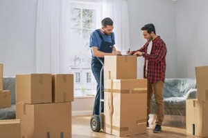 homeowner welcomes professional mover with hand truck full of cardboard boxes