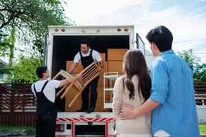 asian couple check while unloading boxes and furniture from a pickup truck to a new house